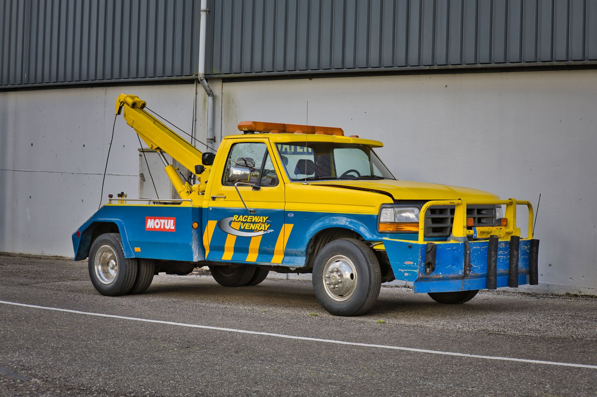 Yellow tow truck parked at Raceway Venray, showcasing automotive support in Ysselsteyn, Netherlands.