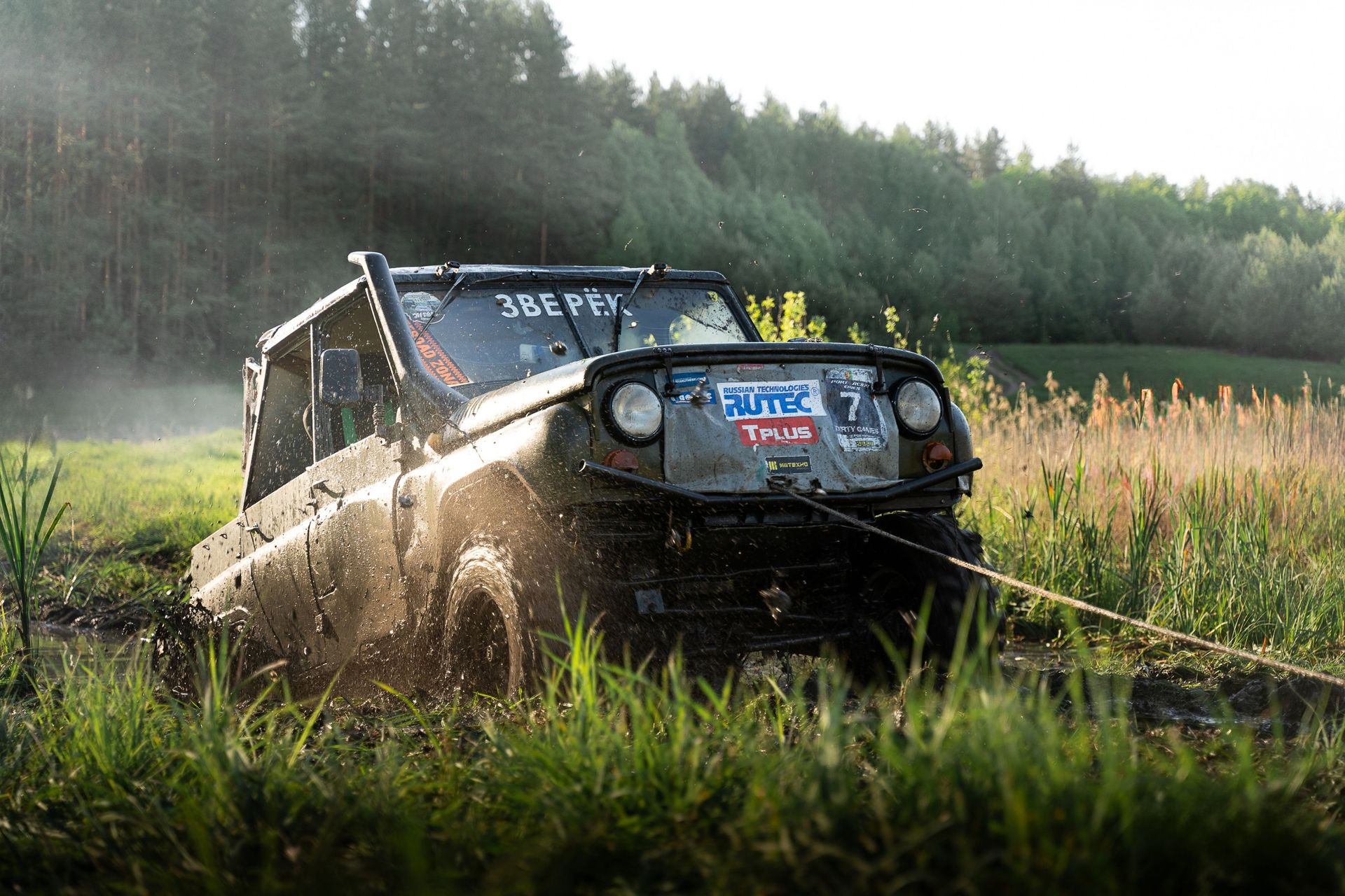 A rugged off-road vehicle plowing through muddy fields during a daytime adventure.