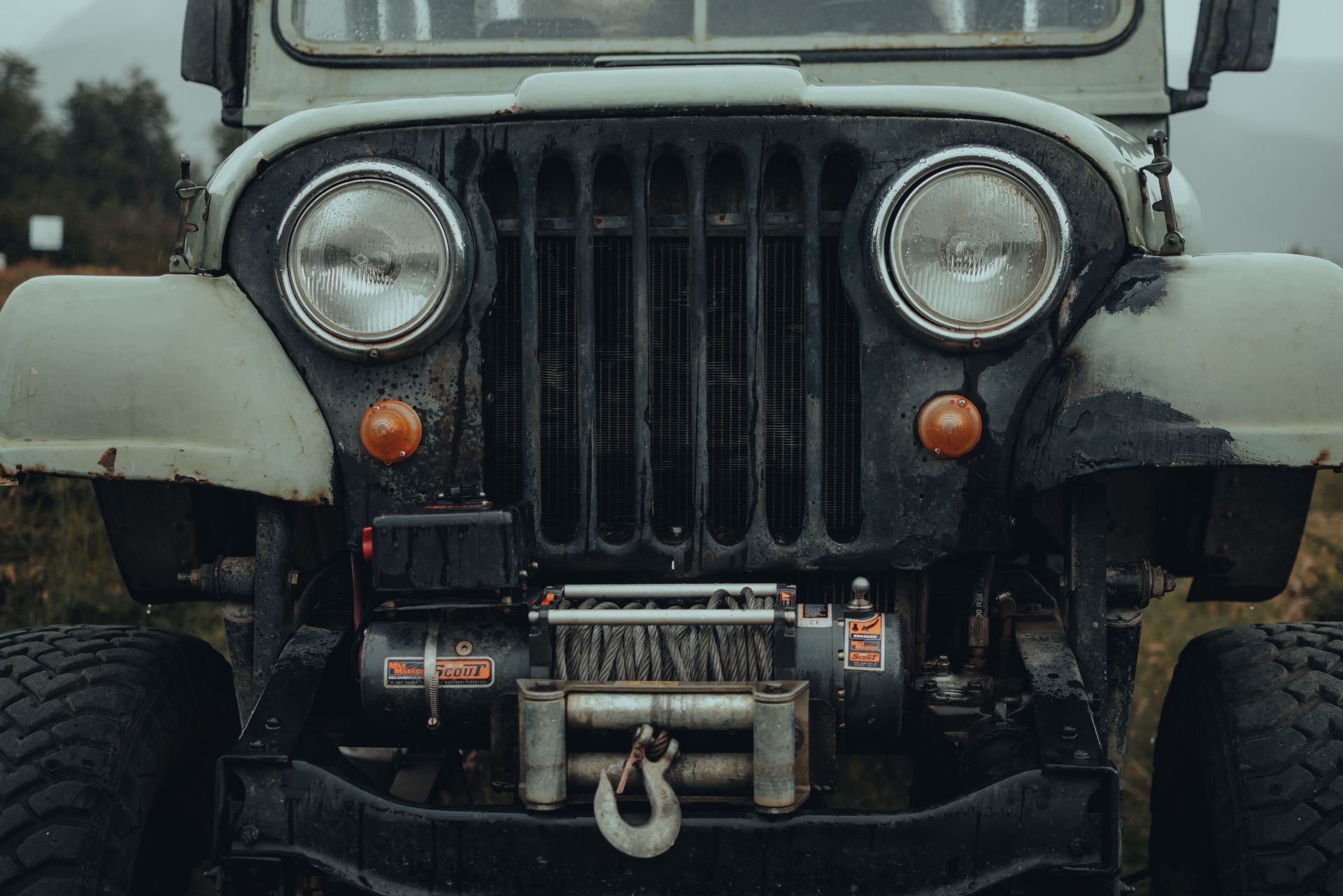Close-up of a rugged vintage jeep showcasing its front grill and headlights. Perfect for adventurous themes.